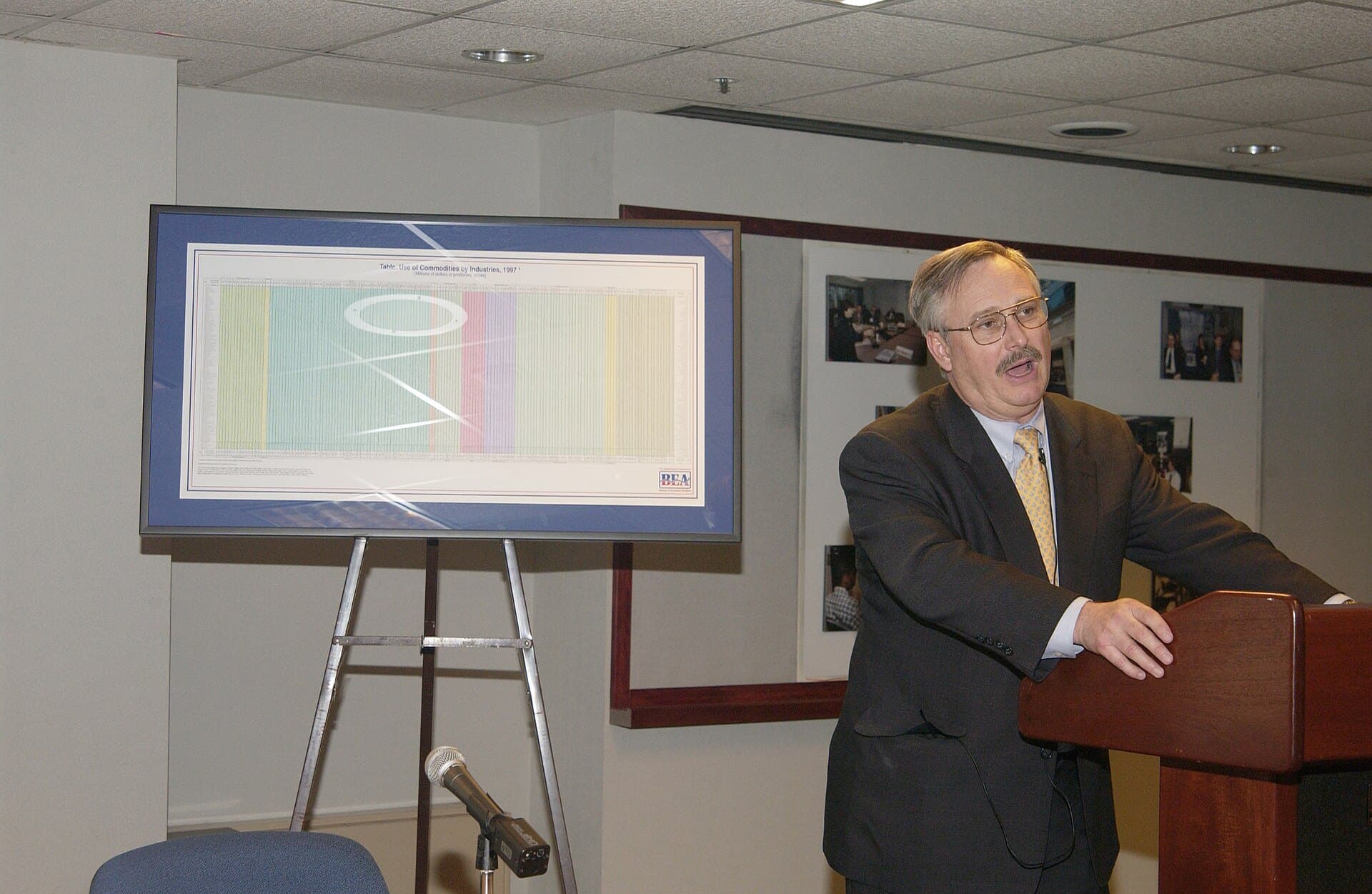 A speaker at the podium beside a display of BEA’s benchmark input-output table at its unveiling, March 2003 (Commerce Department photo, National Archives)