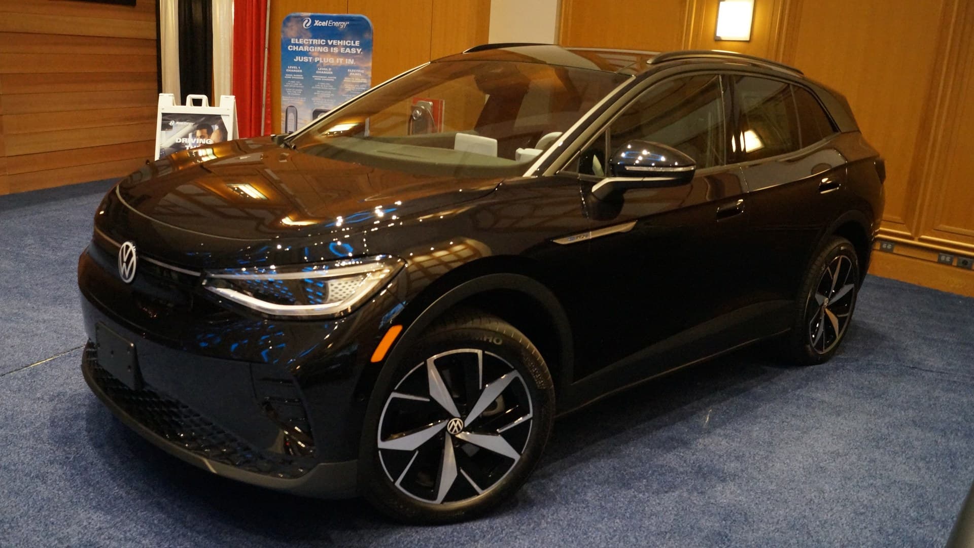 Black Volkswagen ID.4 electric SUV on display indoors, seen from the front left