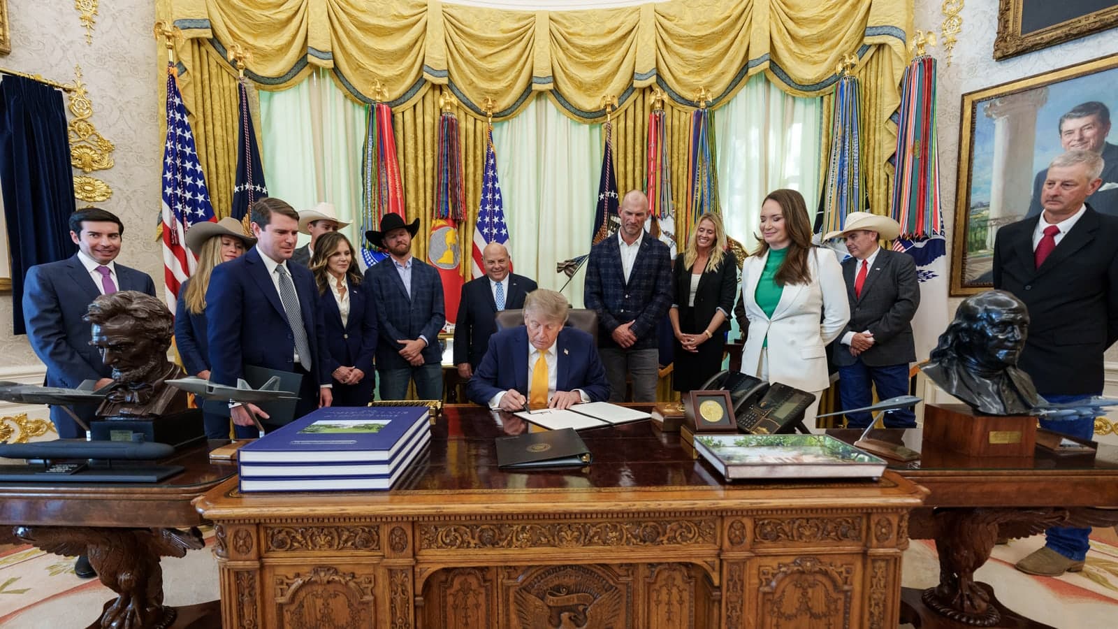 President Donald J. Trump, seated at the Resolute Desk in the Oval Office, signs a document with a thick black marker while aides stand around the desk. File photo, September 4, 2026.