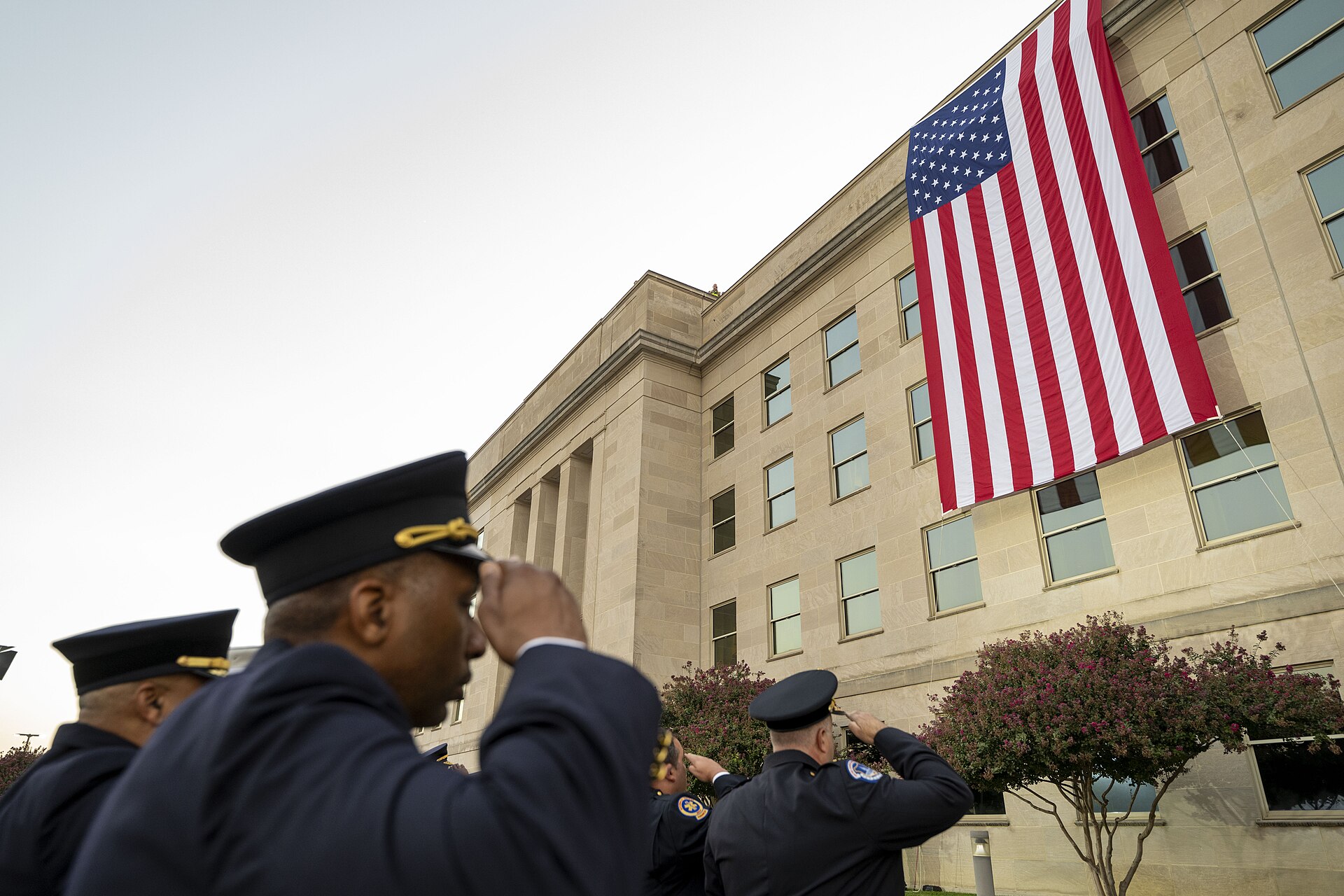 Uniformed officers salute a large American flag on the Pentagon during a September 11 observance